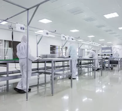 Profissionais em laboratório farmacêutico com sistema de exaustão e ambiente controlado para garantir segurança e qualidade.