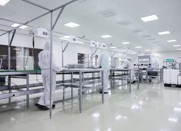 Profissionais em laboratório farmacêutico com sistema de exaustão e ambiente controlado para garantir segurança e qualidade.