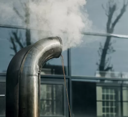 Tubo de sistema de exaustão liberando vapor, representando o funcionamento de sistemas de exaustão para controle de poeira metálica.