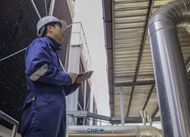 Técnico realiza manutenção preventiva em sistema de exaustão industrial para garantir segurança e eficiência operacional.