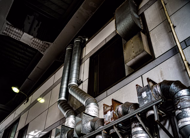 Sistema de extração de fumaça industrial com dutos metálicos instalados em galpão para controle de fumaça e segurança operacional